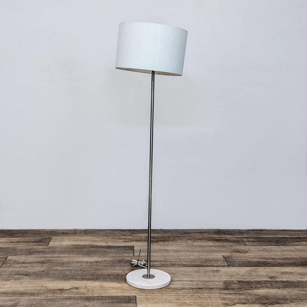 Side view of tall Reperch floor lamp with round base and shade.