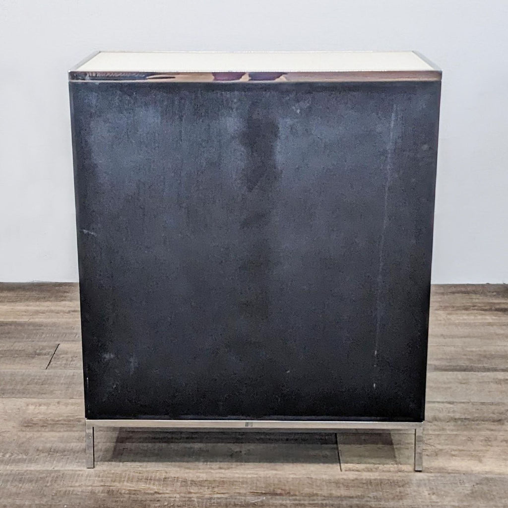 Back view of a black cabinet with metal legs and a white top.