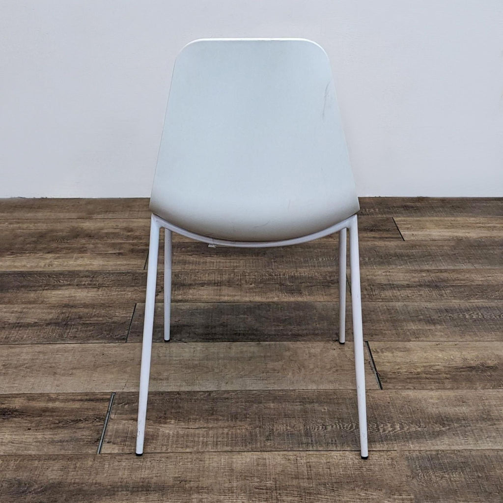 3. Rear angle of a minimalist Reperch dining chair with a scooped seat and slim powder-coated legs on wood flooring.