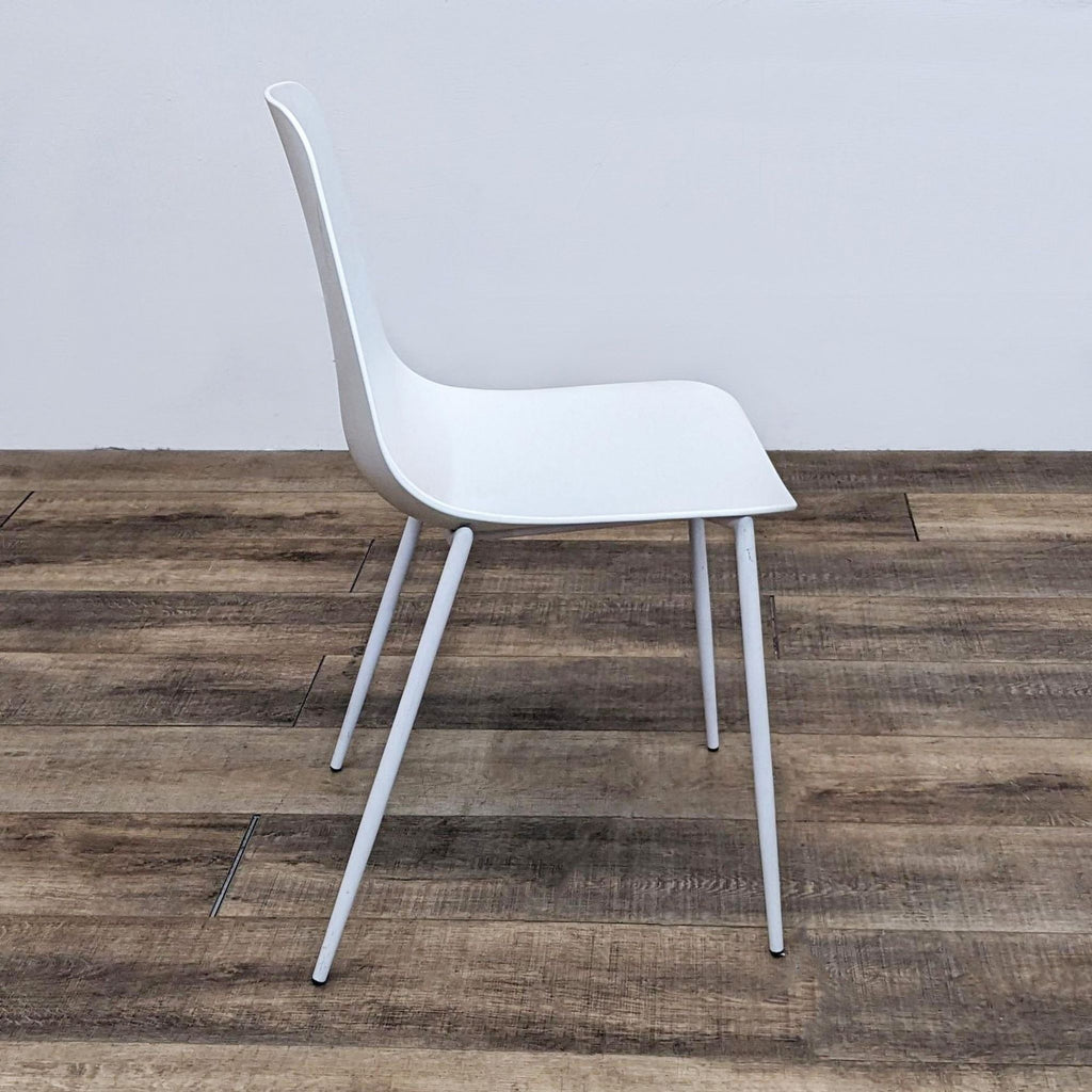 2. Side view of a modern Reperch dining chair, featuring a curved polypropylene seat and powder-coated legs.