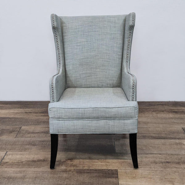 Front view of a modern wingback chair with nailhead trim and tapered legs.