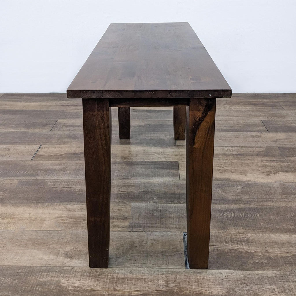 Side view of a narrow, rustic wooden console table with a smooth surface.