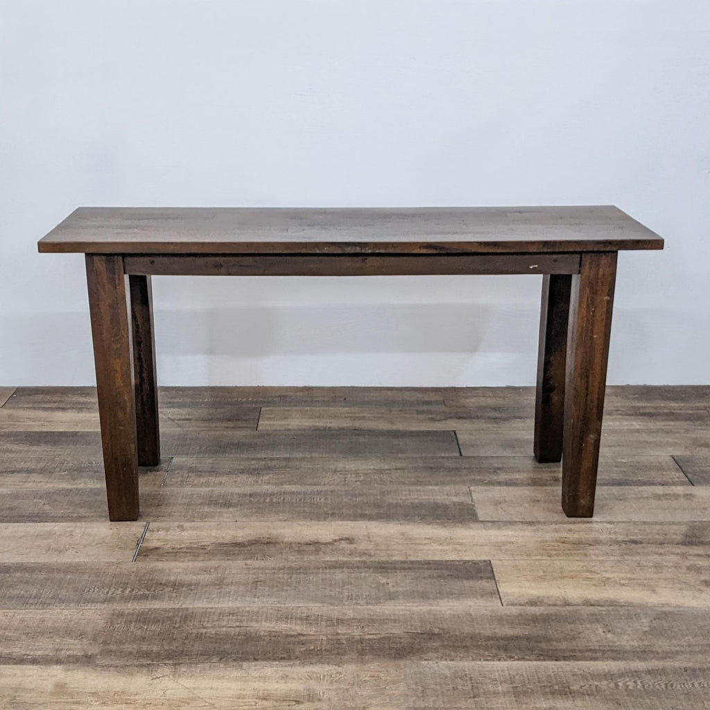 Dark wooden console table with sturdy legs, placed on a wooden floor.