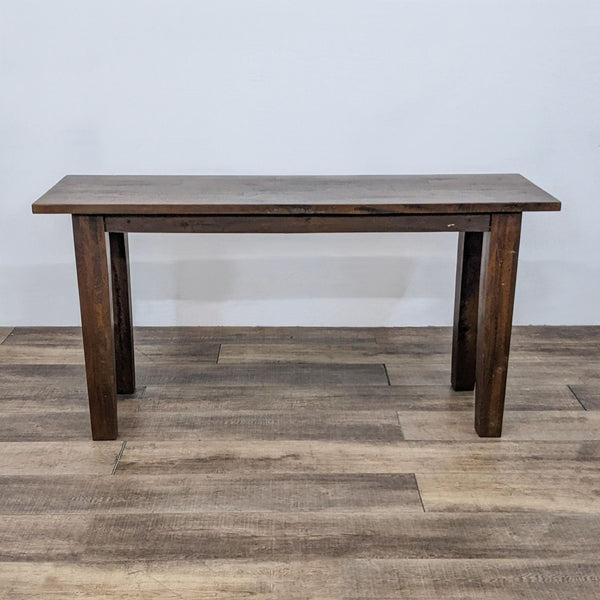 Dark wooden console table with sturdy legs, placed on a wooden floor.