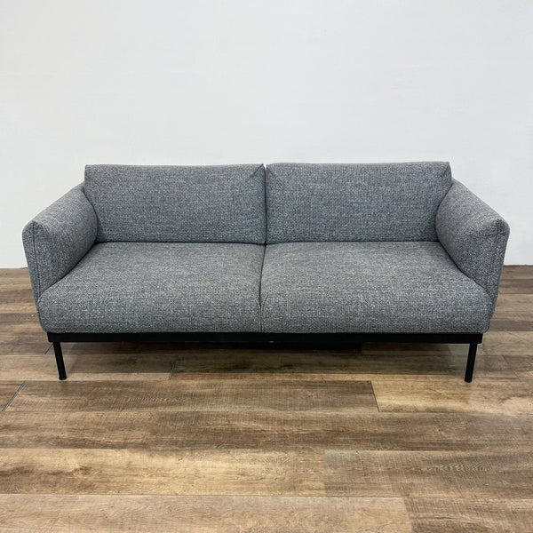 Modern gray fabric loveseat with dark metal base and legs, in a minimalist design.  