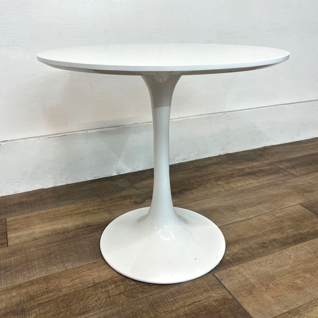 Mid-Century Modern dining table with round wood top, tulip-style metal base.