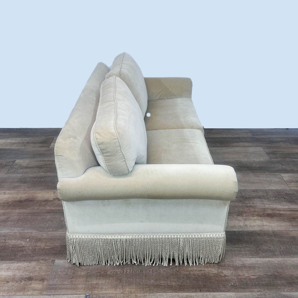 Compact camel sofa with fringe-trimmed base and rolled arms.
