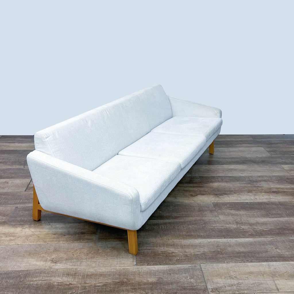 Side view of HD Buttercup 3-seat sofa, white upholstery, wood frame, and legs on wooden flooring.