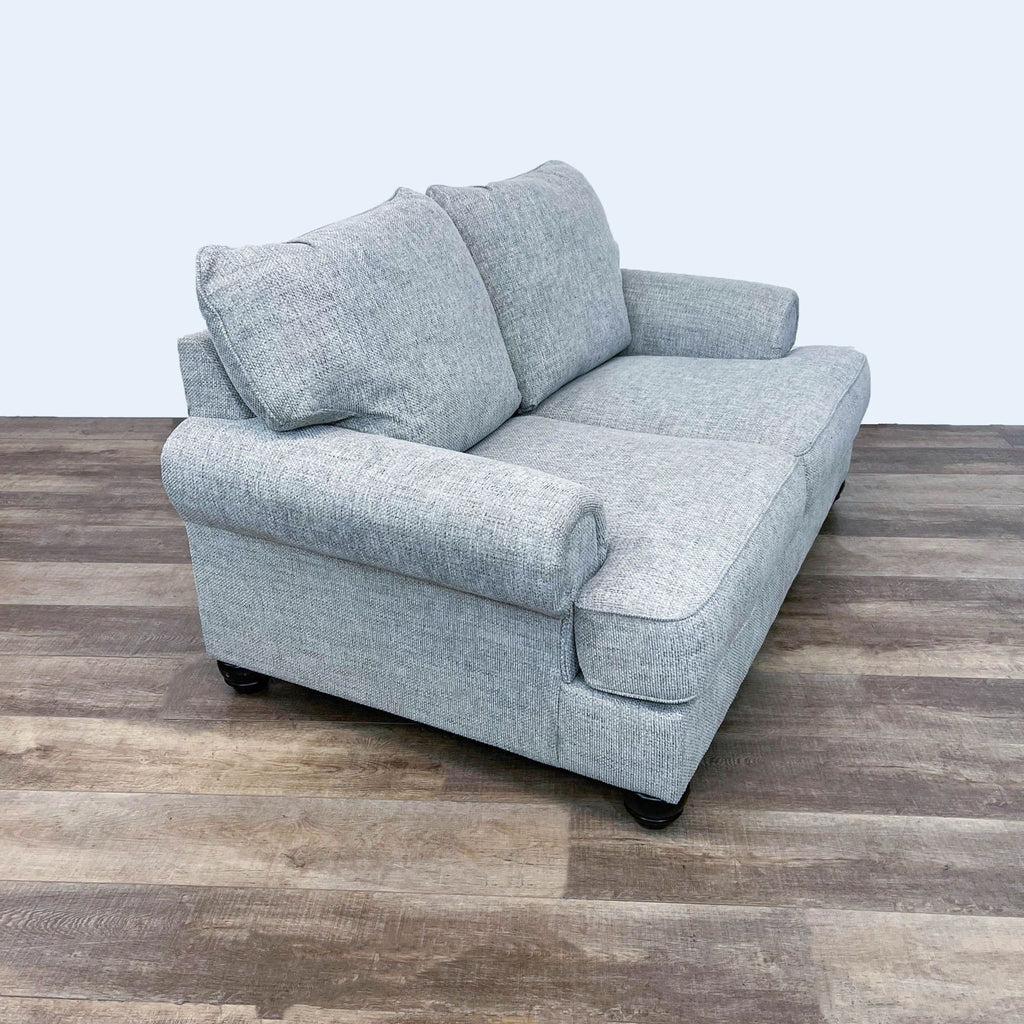 2. Side angle of Reperch loveseat in light grey fabric upholstery with rolled arms and dark bun feet.  