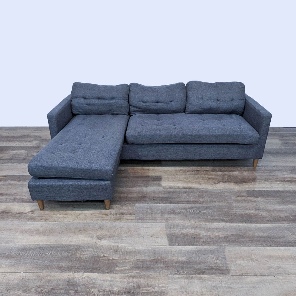 Mid-century modern sectional with tufted cushions, narrow arms, and chaise.