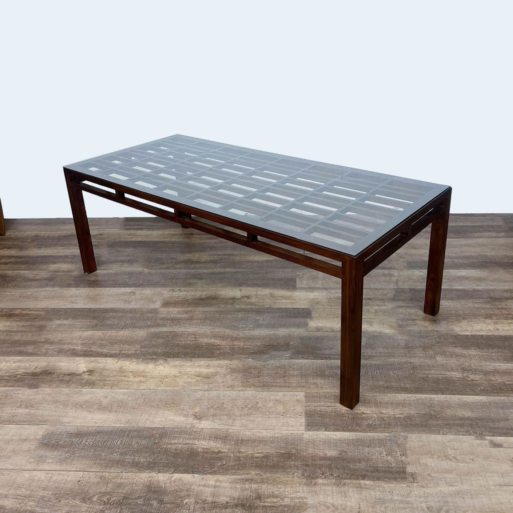 Reperch dining table with glass top, geometric wood design, and pierced apron.