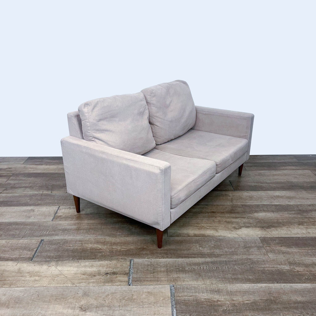 Side view of a gray loveseat featuring sleek design and modern tapered legs.  