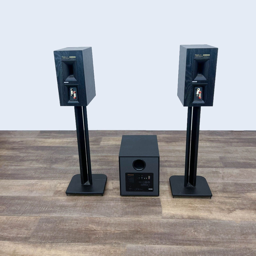Klipsch audio setup with two speakers on stands, and a subwoofer on the wooden floor.