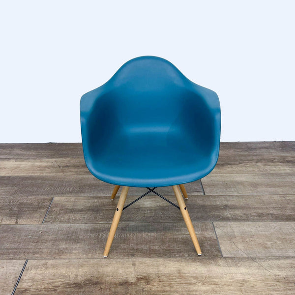 Modern blue armchair with a matte plastic seat and Eiffel style wood base.