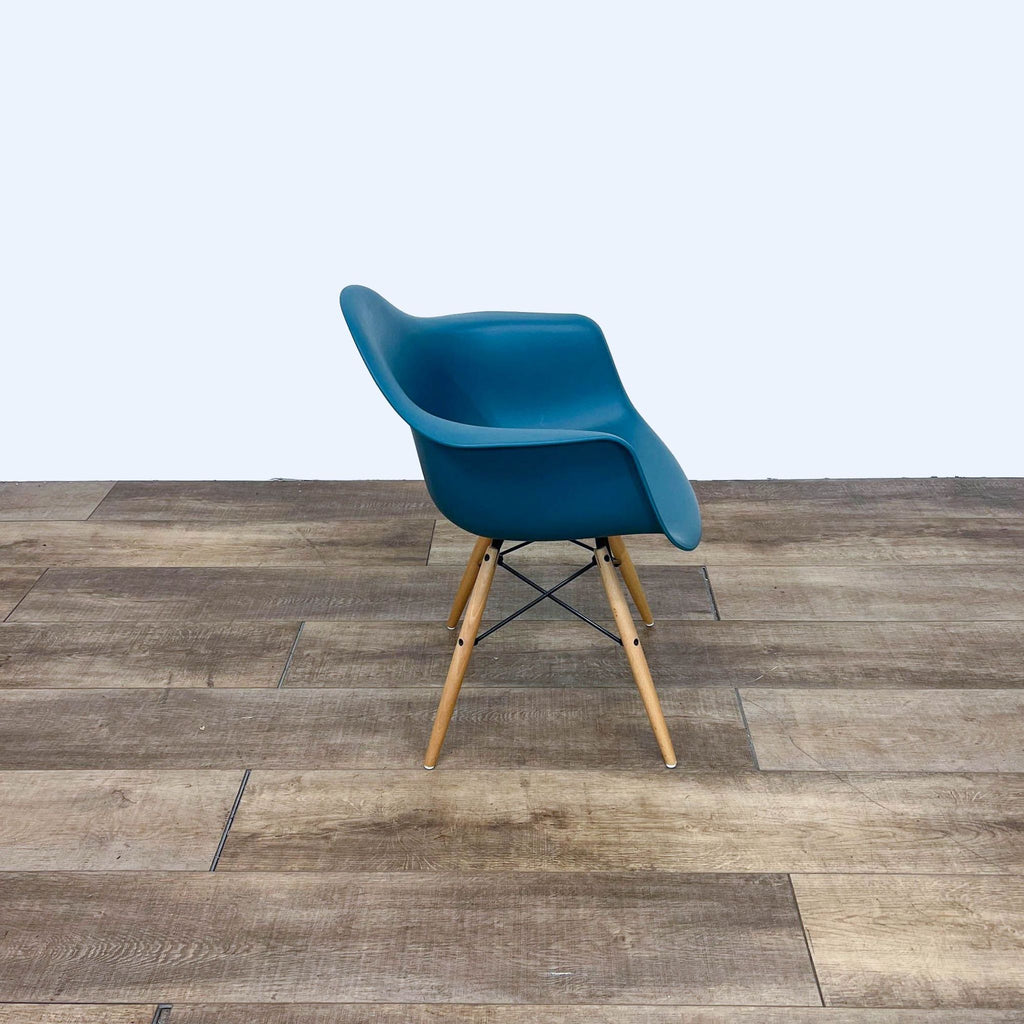 Side view of blue armchair featuring wooden legs with wire support.