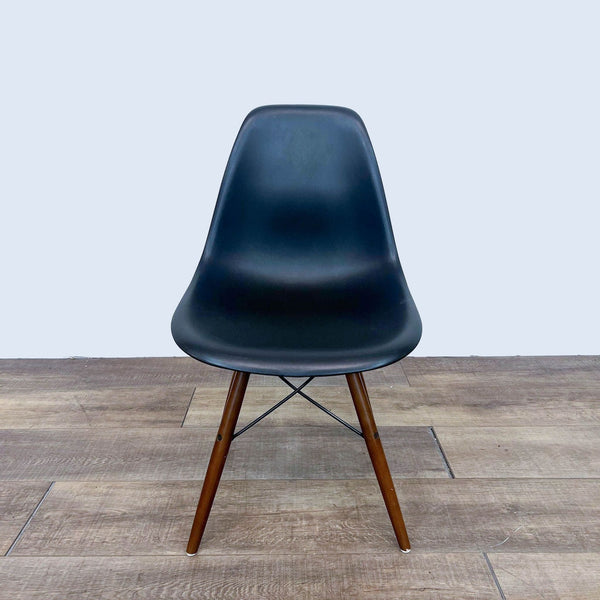 Front view of a black dining chair with a wood and metal Eiffel style base.