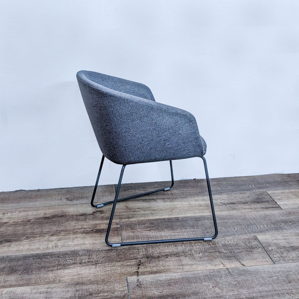 Side view of upholstered grey chair with elegant steel legs.