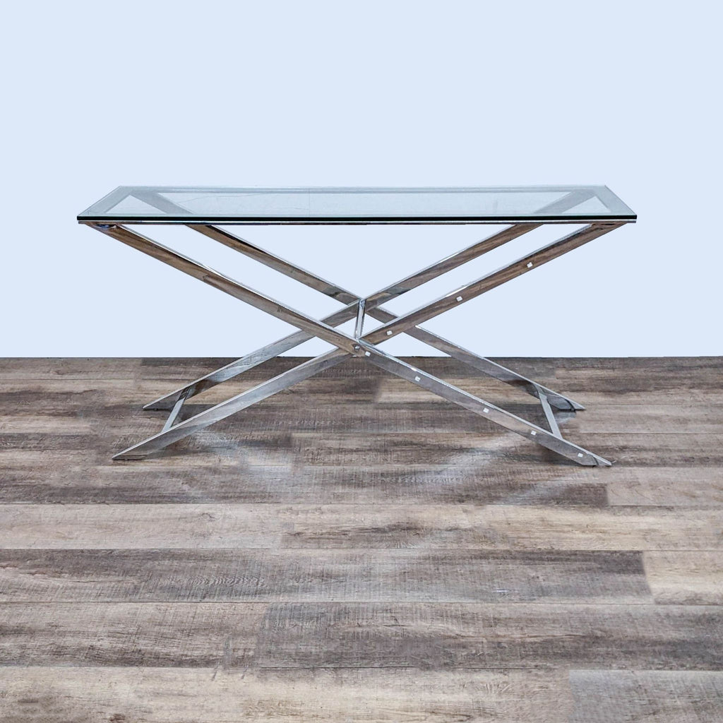 Reperch side table with glass top and metal X-frame on wooden floor.