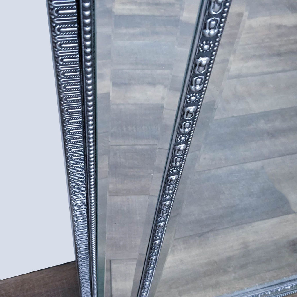 Close-up of the beveled mirror frame showcasing intricate antique silver detailing.