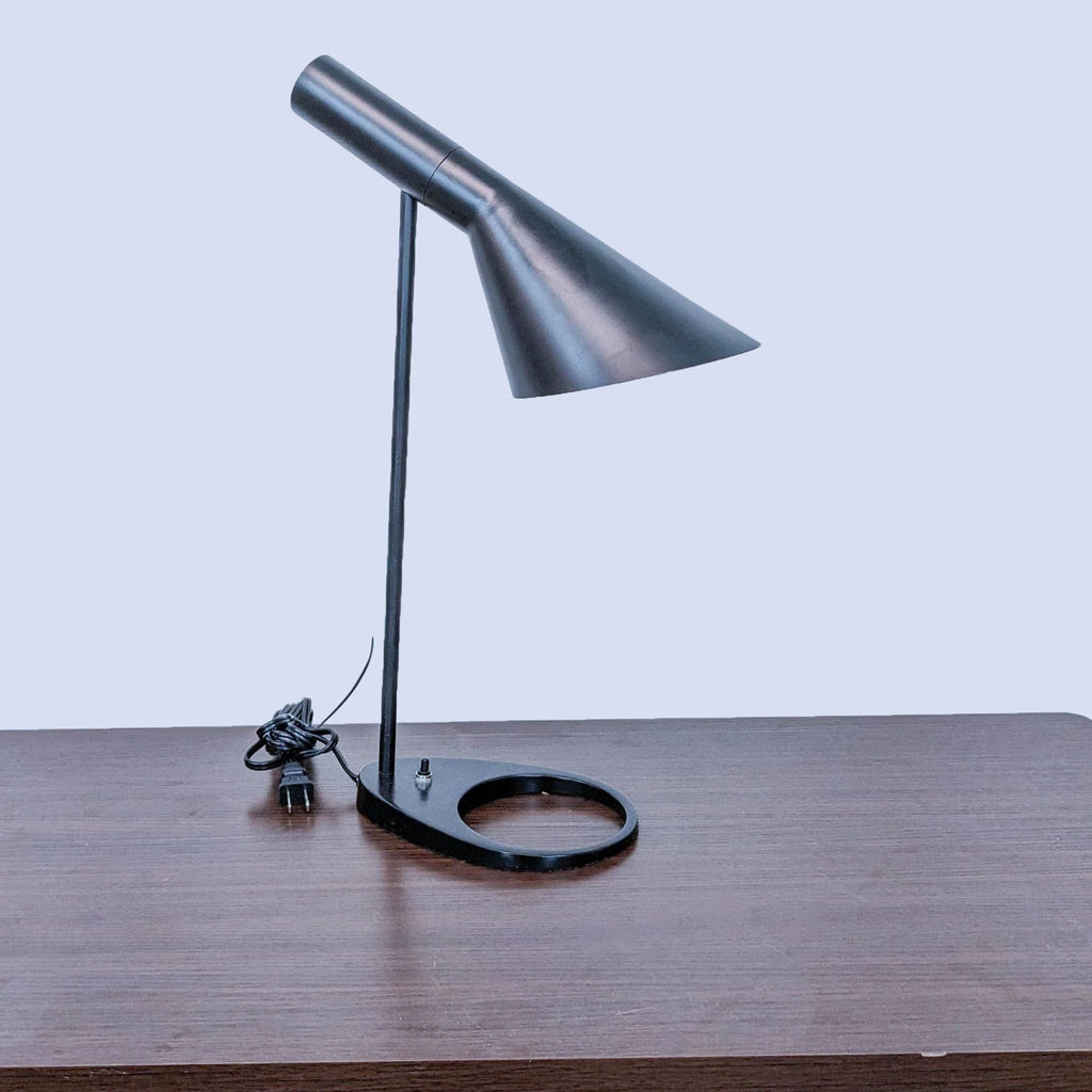 Minimalist black desk lamp by Reperch, featuring a streamlined design and a circular base.