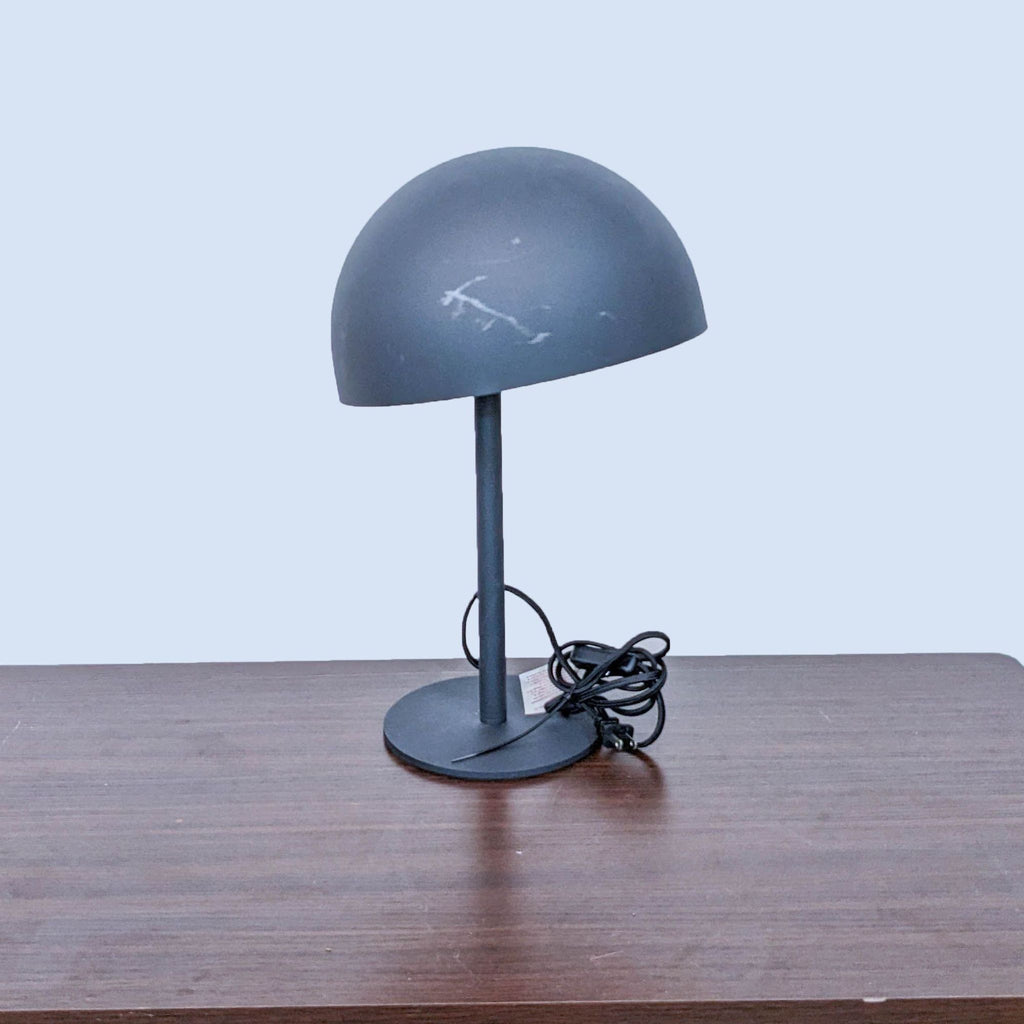 Side view of Reperch lamp with cord on a wooden table.