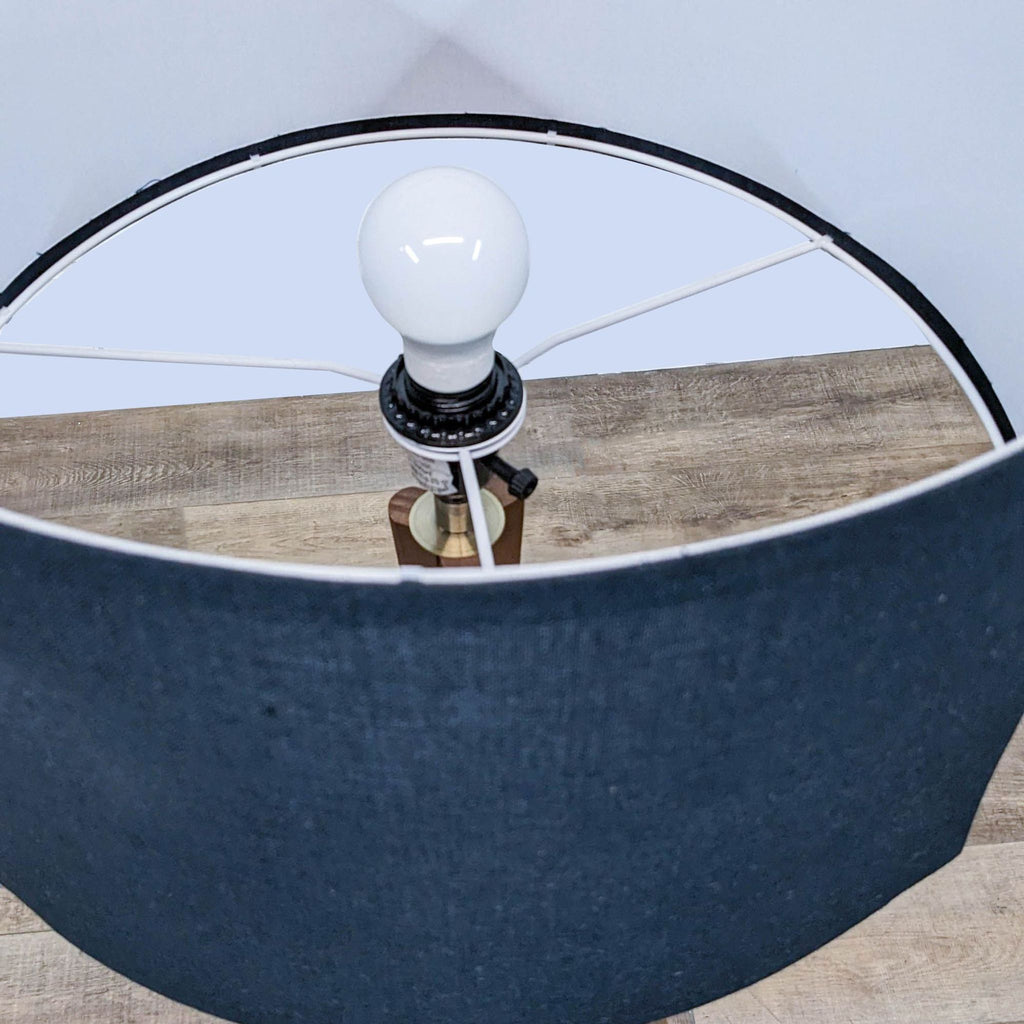 Top view of a floor lamp with a blue fabric shade and white bulb.