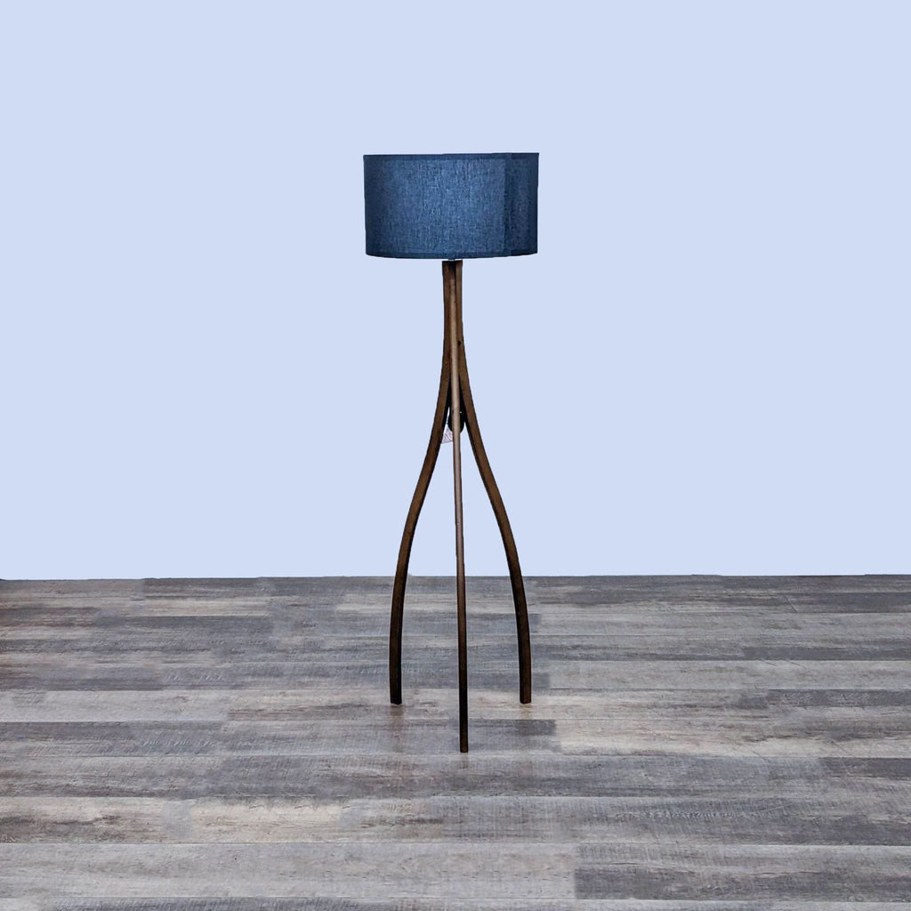 Stylish floor lamp with a smooth wooden base and blue shade on wooden floor.