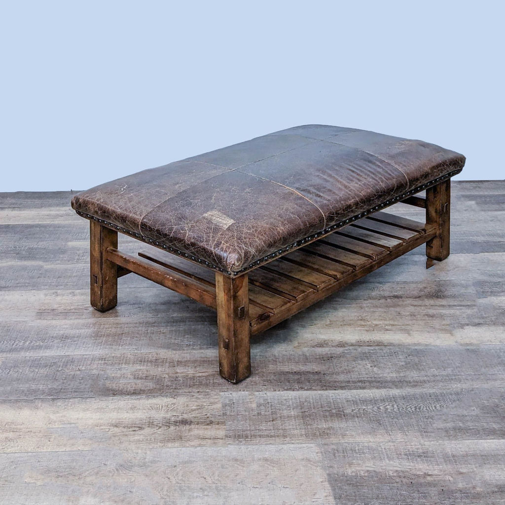 2. Williams-Sonoma brown leather top wood ottoman with shelf and nailhead detail, angled perspective.