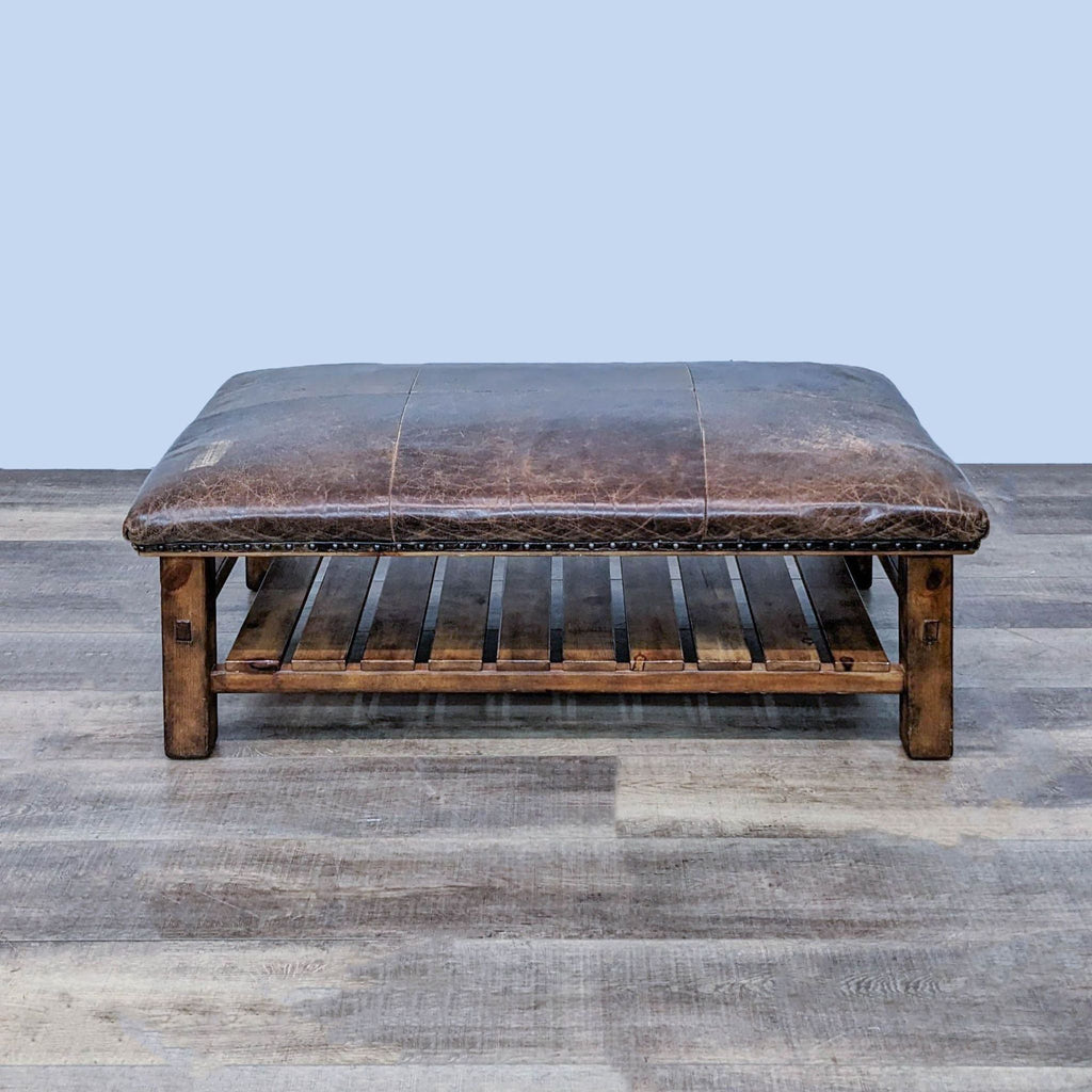 1. Large rectangular brown distressed leather ottoman on wood frame with shelf and nail head accents, front view.
