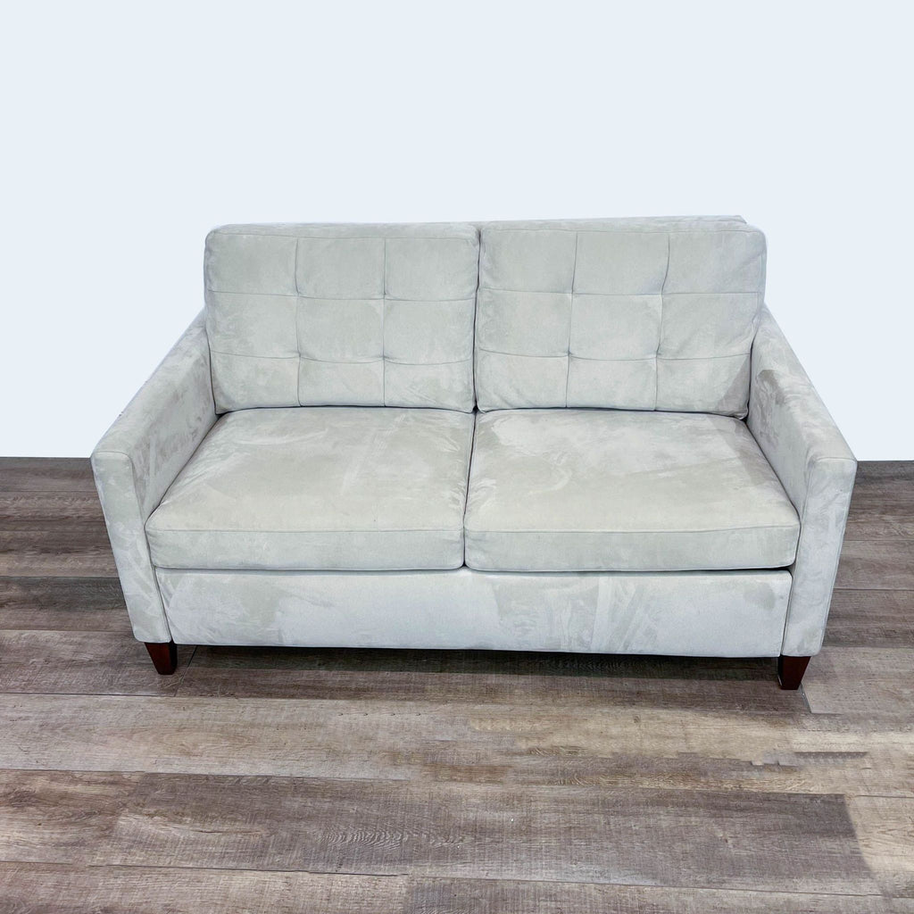 Compact 64" tufted loveseat with plush cushions on wooden floor.