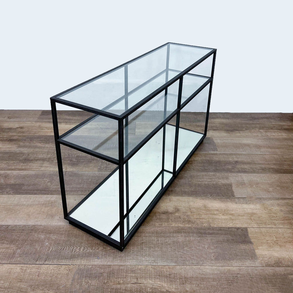 Side angle of a glass and mirrored shelf table on metal frame.