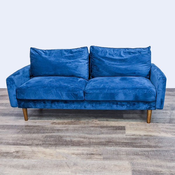 Low-profile blue sofa with clean lines, narrow arms, and tapered legs on a wooden floor.
