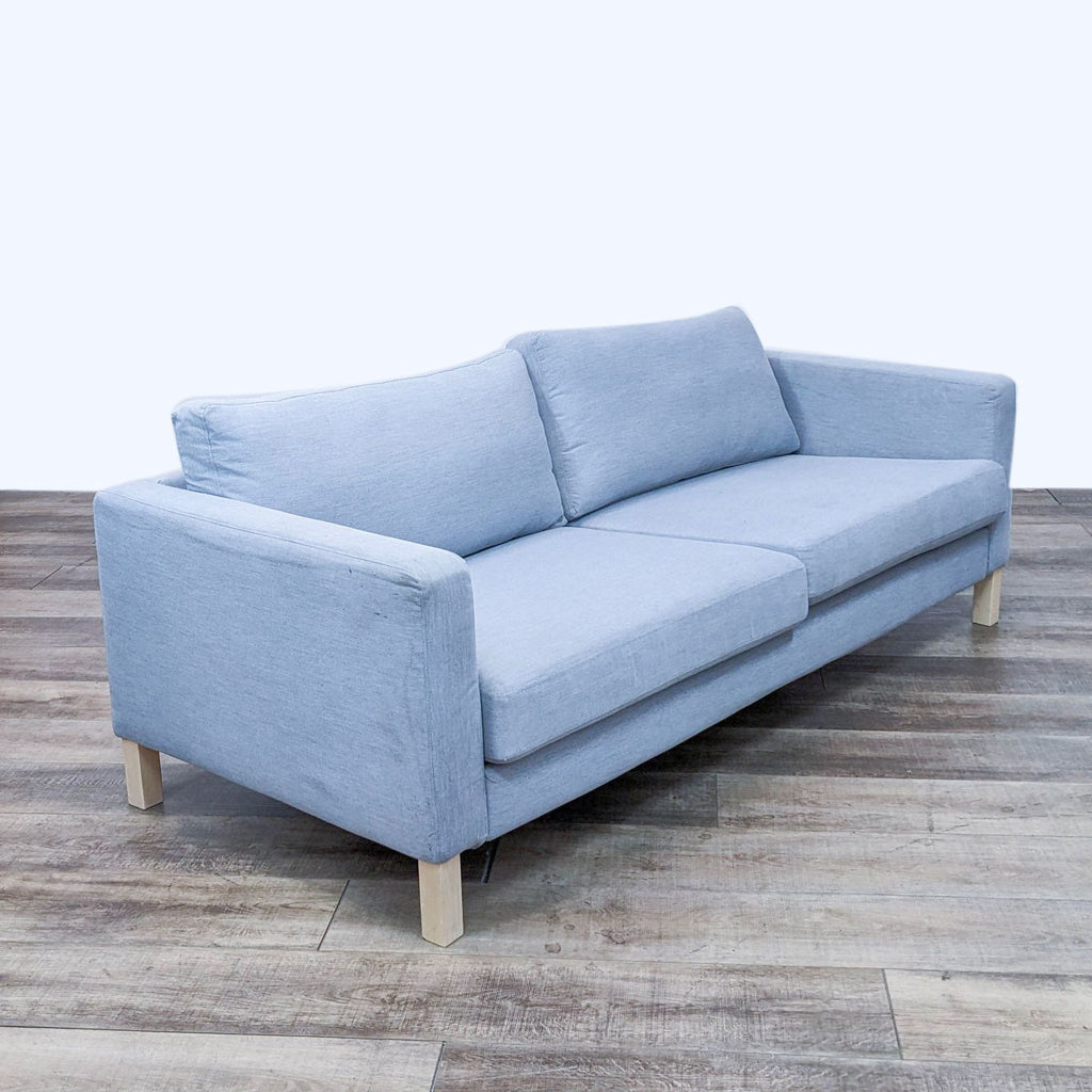 Angled view of light blue Ikea sofa, highlighting track arms and 80" length.