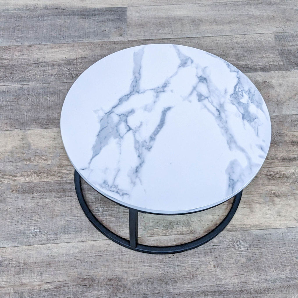 Close-up of a marble-patterned round tabletop with black metal frame.