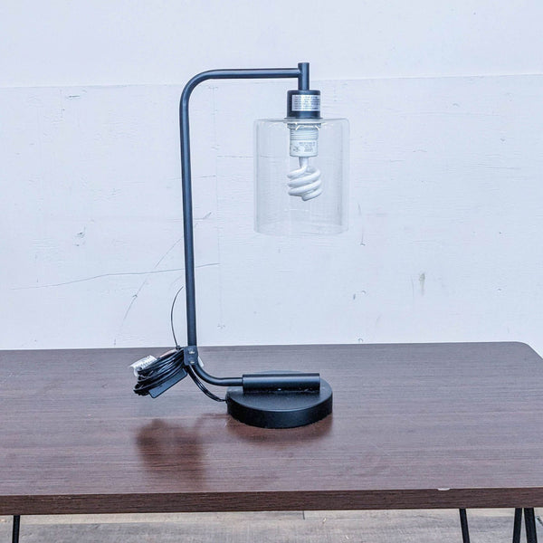 A Reperch lamp with a spiral bulb and clear glass shade on a wooden table.