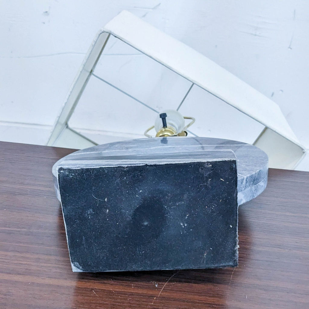 Bottom view of Reperch lamp base with detached white shade on wooden surface.