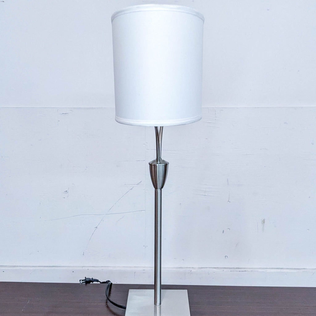 Contemporary table lamp featuring a tall white drum shade on a metal stand.