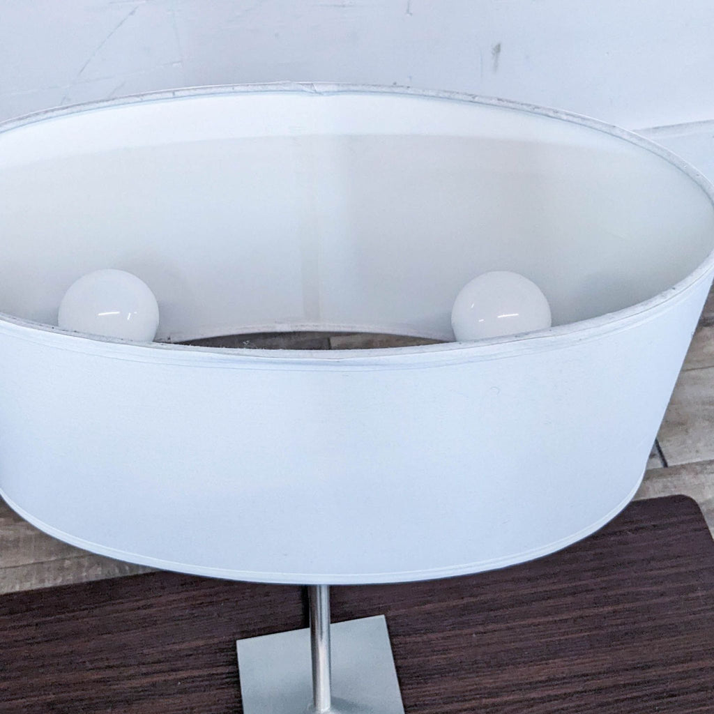 Close-up view of a white lampshade with two visible light bulbs inside.