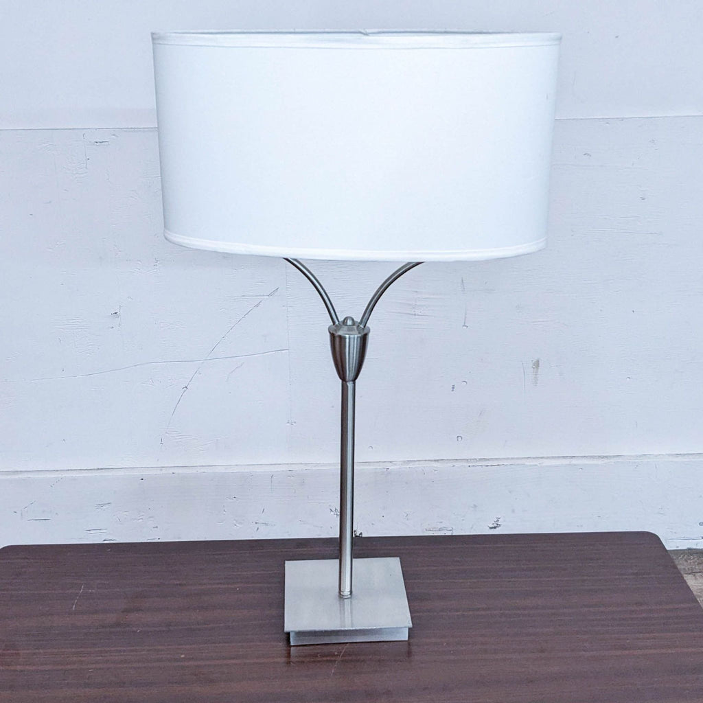 Modern table lamp with a white cylindrical shade and sleek metal base.