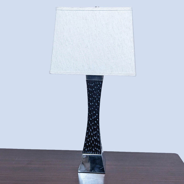 Reperch lamp with textured black base and white shade on a wooden table.