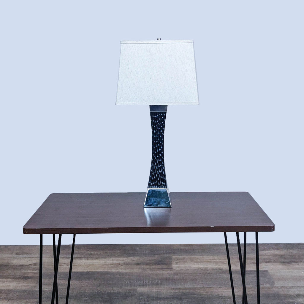 Reperch lamp on wood table with hairpin legs, light background.