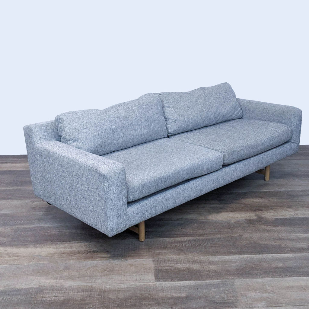 Angled view of a gray 3-seat sofa, featuring light wood legs and block arms.