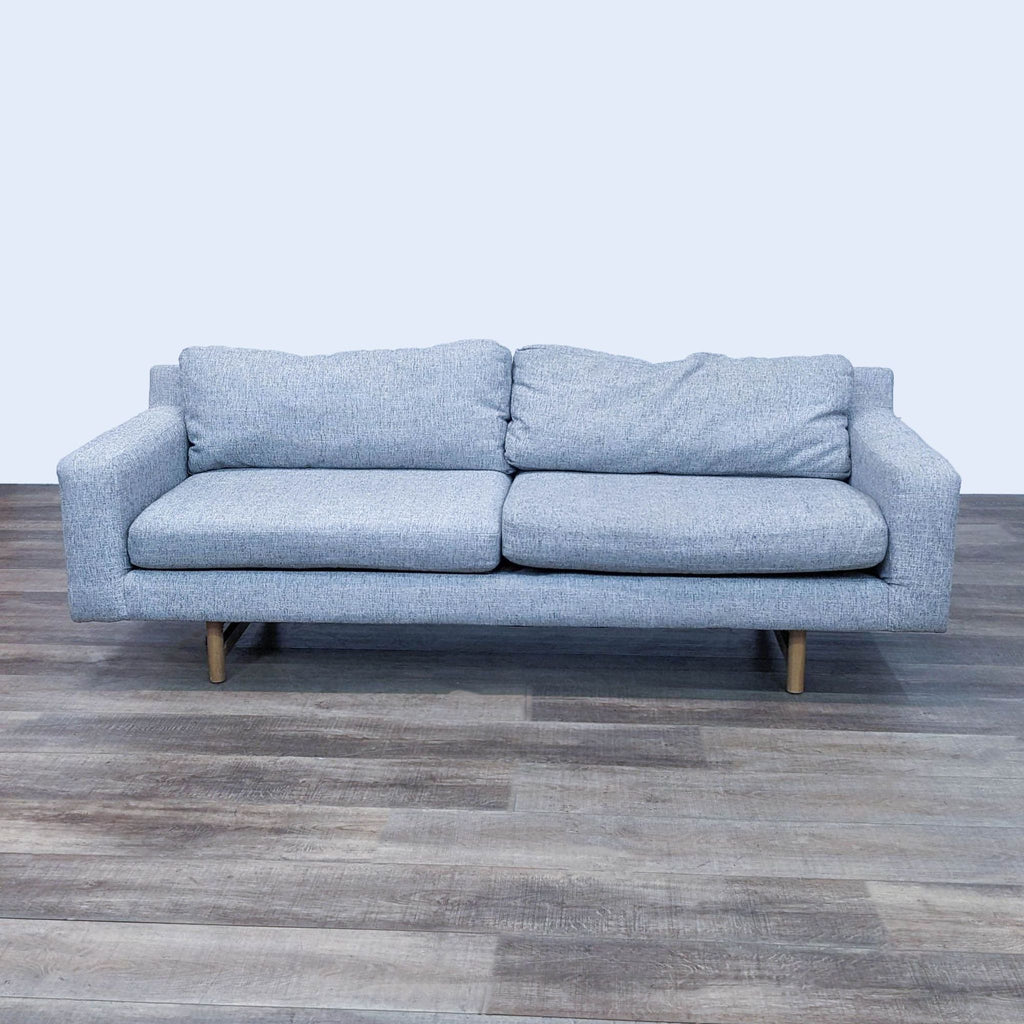 Gray 3-seat sofa with block arms and light wood feet on a wooden floor.