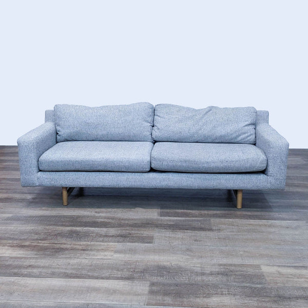 Gray 3-seat sofa with block arms and light wood feet on a wooden floor.