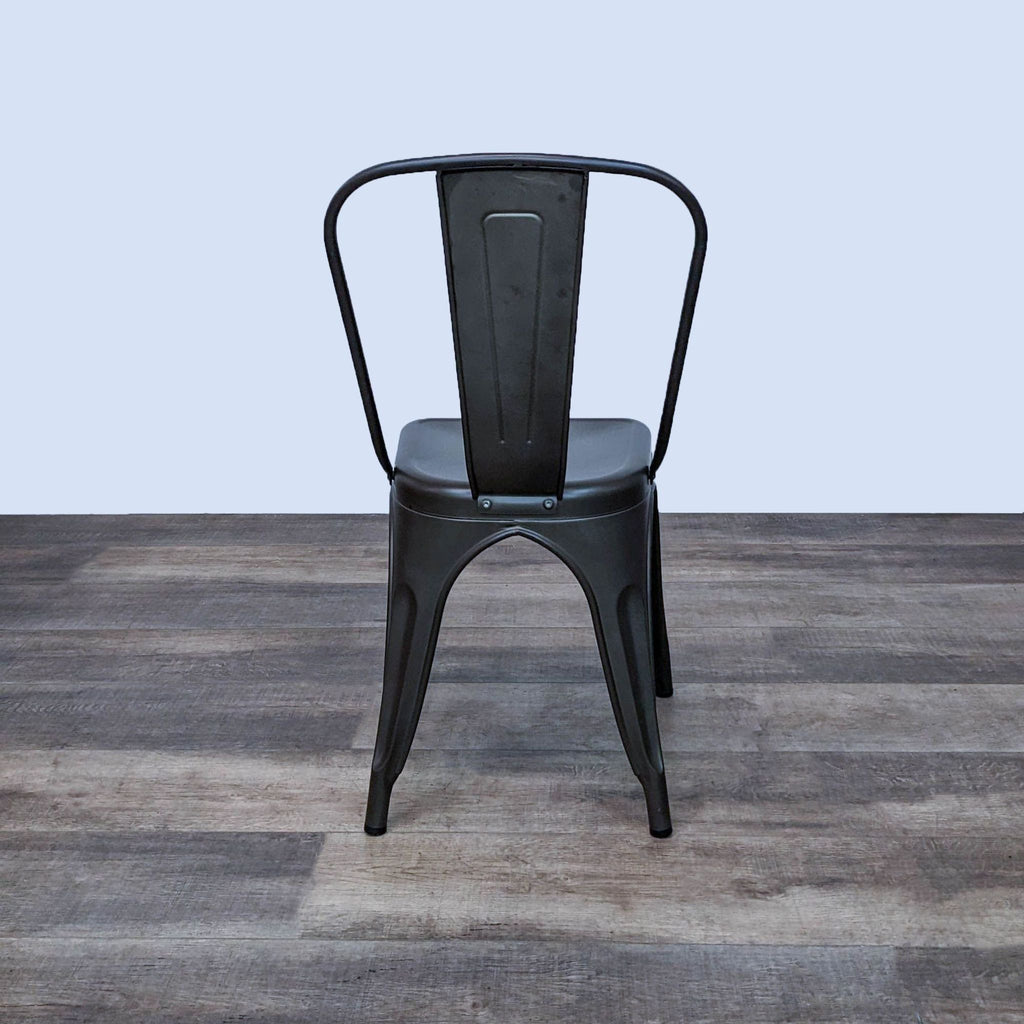 Back view of a black metal dining chair featuring an industrial style and curved edges.