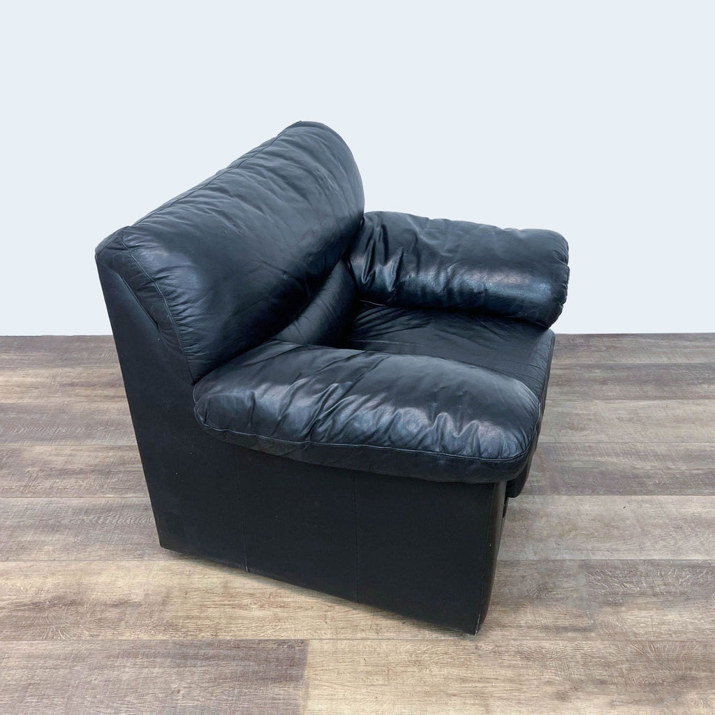 Plush black leather chair with overstuffed back and arms.