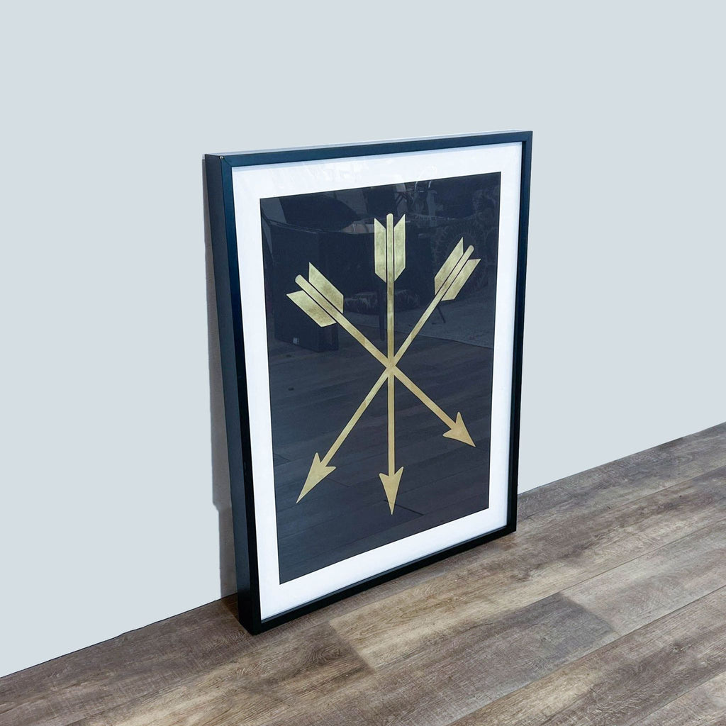 Gold arrows designed on black paper in a sleek frame, viewed from the side on a wooden surface.