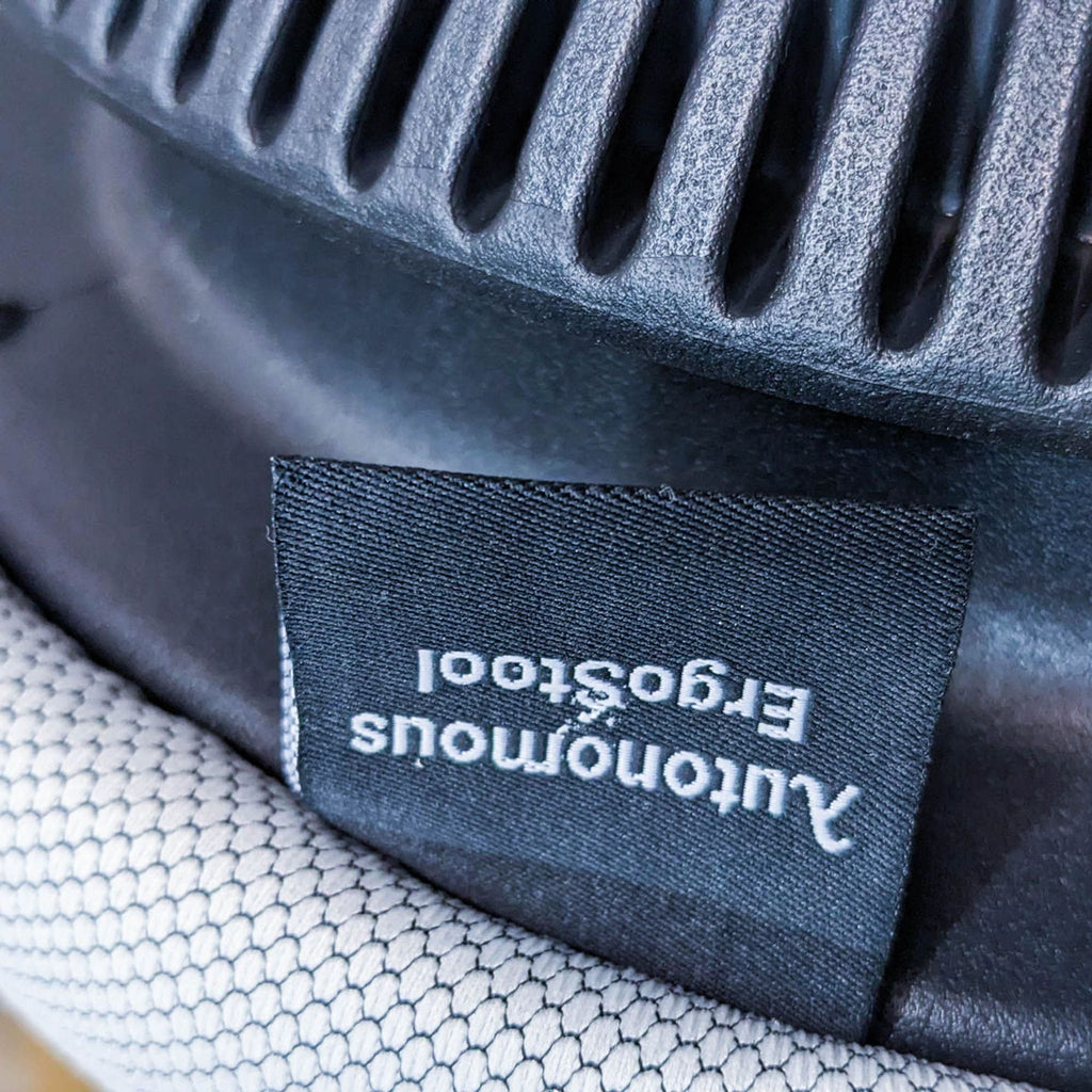 Fabric tag on an ergonomic stool showing the brand logo.
