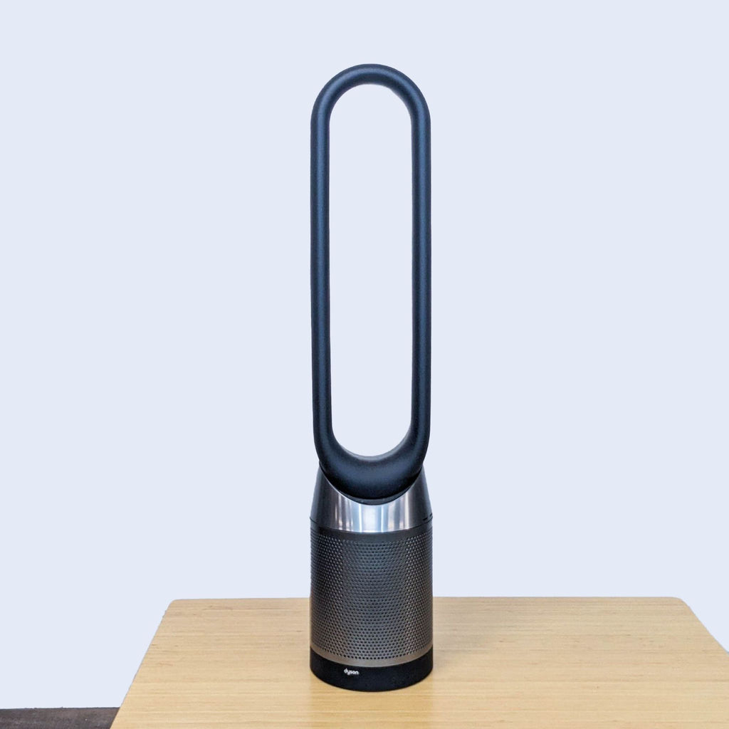 Dyson bladeless fan with sleek vertical design on a wooden table.
