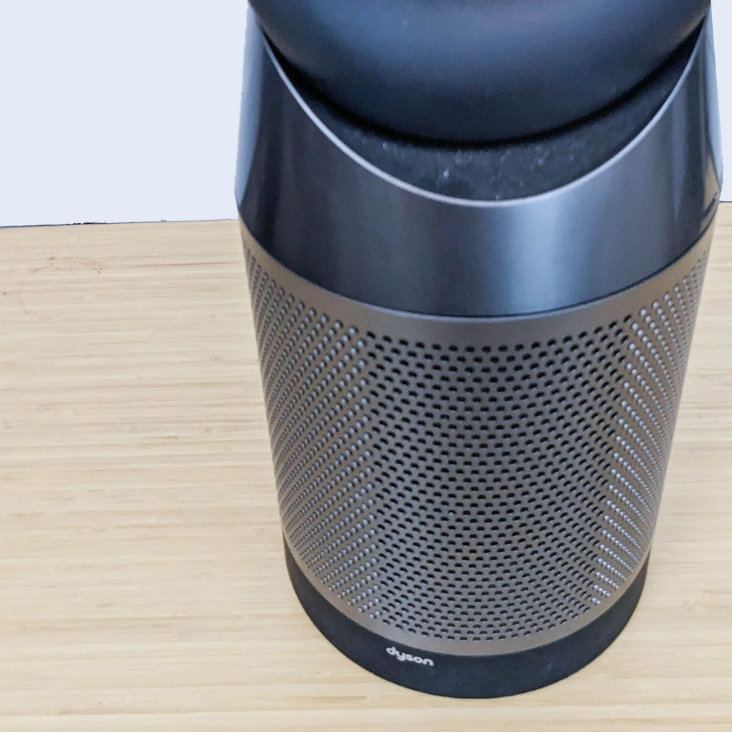 Dyson fan base with perforated design on a wooden surface.